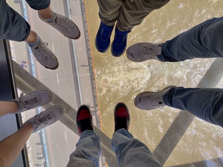 Unsere Familie steht auf dem Glasboden der Tower Bridge in London und blickt auf die Straße und die Themse unter uns