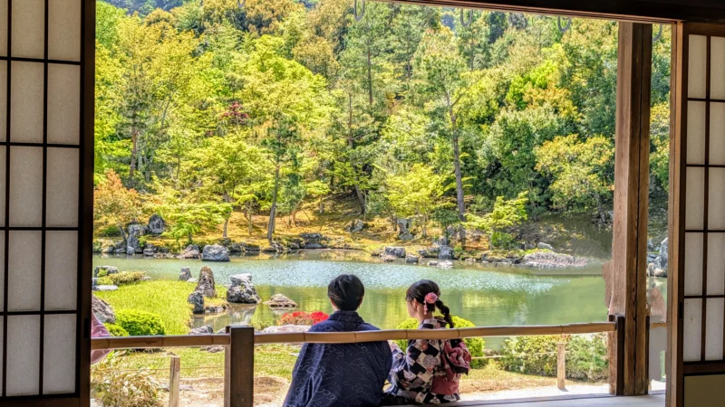 Kyoto mit Kindern – Blick aus einem traditionellen Tempel auf einen japanischen Garten mit sitzendem Paar